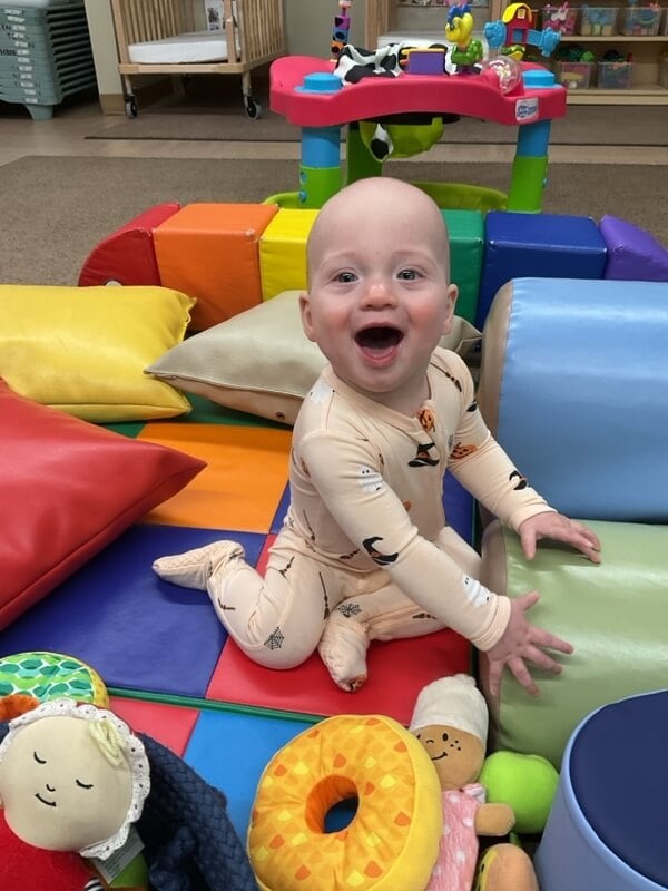 infants spend time with their teachers on the floor with soft toys and climbers