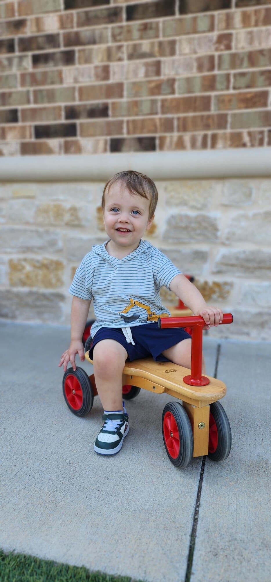 Toddler riding a bike during outdoor play to build gross motor skills at Primrose School at Alliance