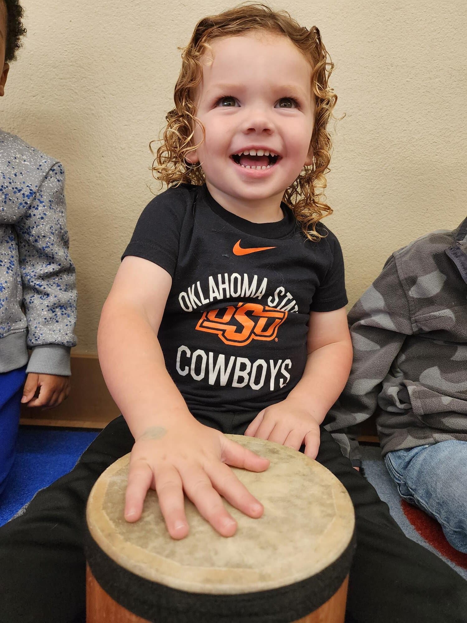 Toddler playing a drum during music time in the classroom