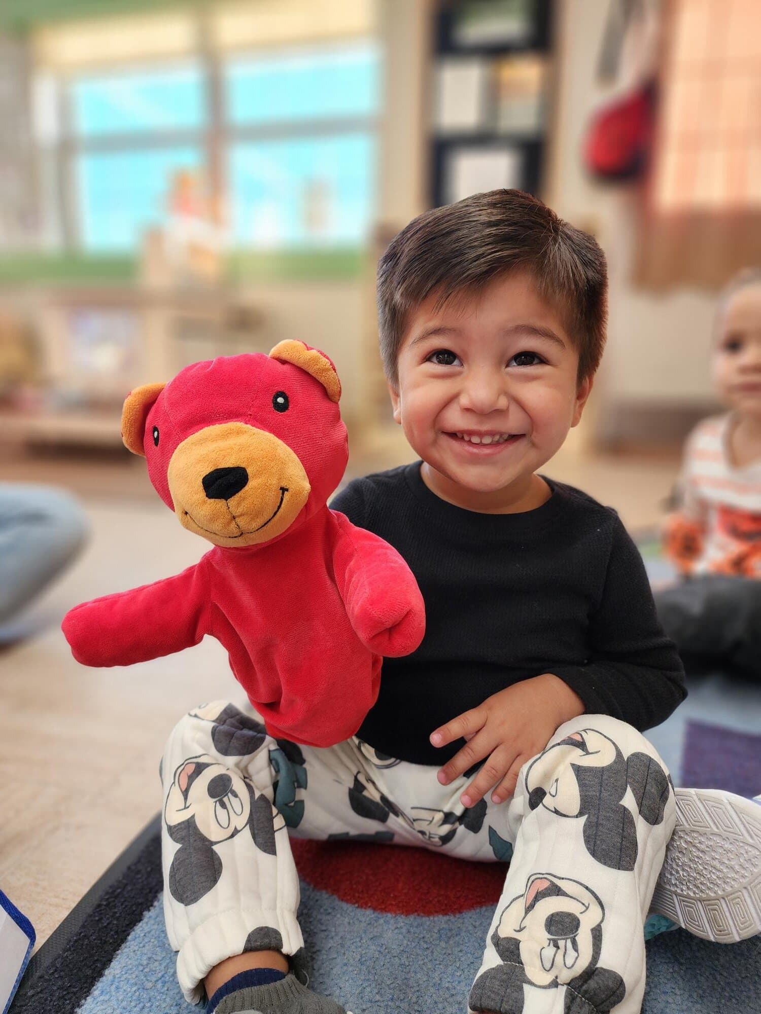 Preschool student holding a classroom puppet during imaginative learning activity