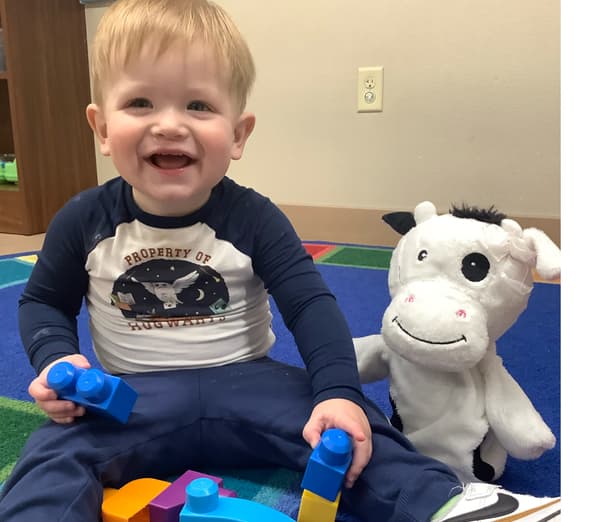 Infant exploring Legos and puppets at Fort Worth preschool.