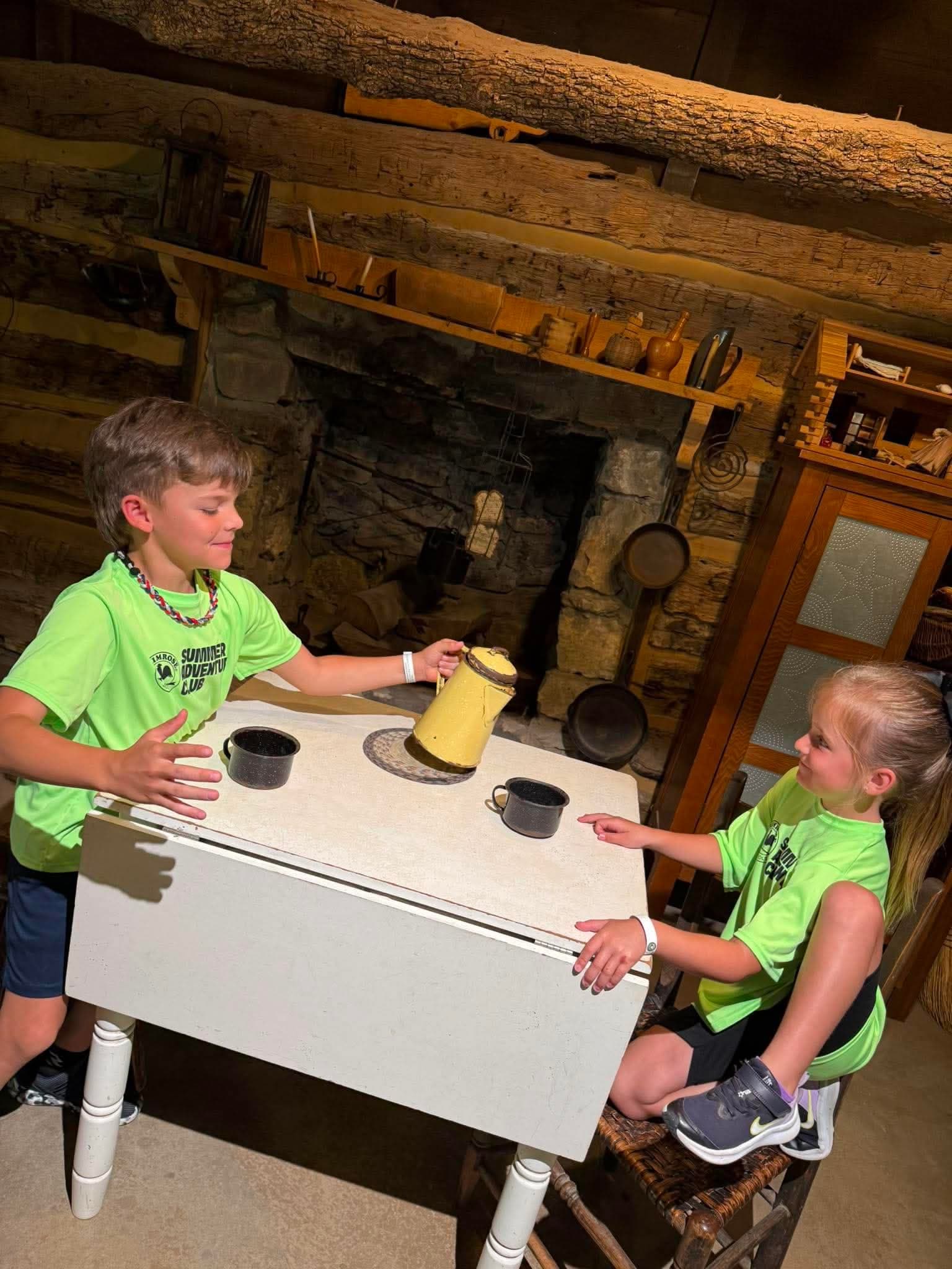 Explorer kids sitting down pretending to have a tea party. 