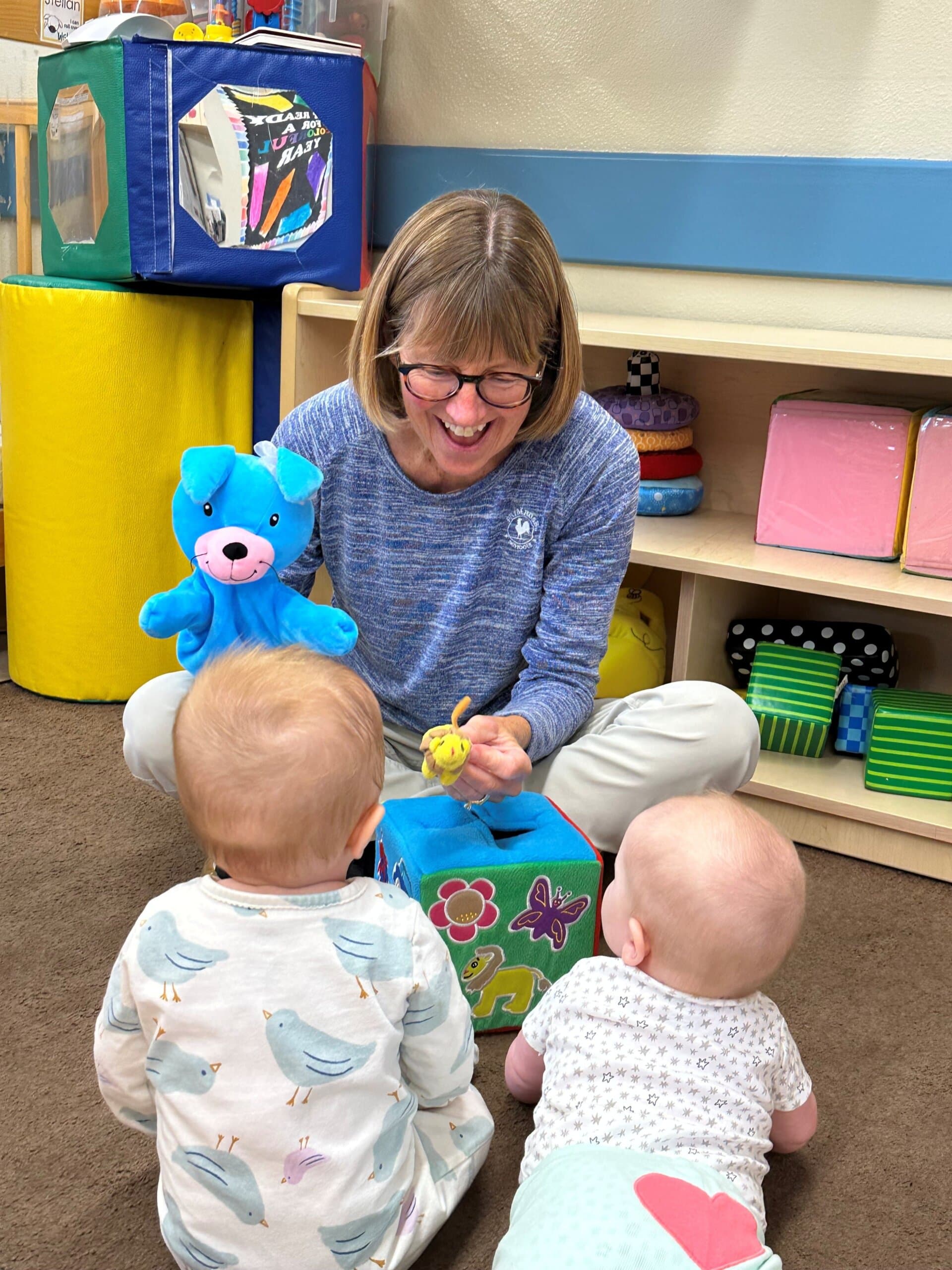 Infant teacher Katie engaging two young babies with puppet play in the infant room at Primrose School of Eagan, a top-rated infant daycare in Eagan, MN