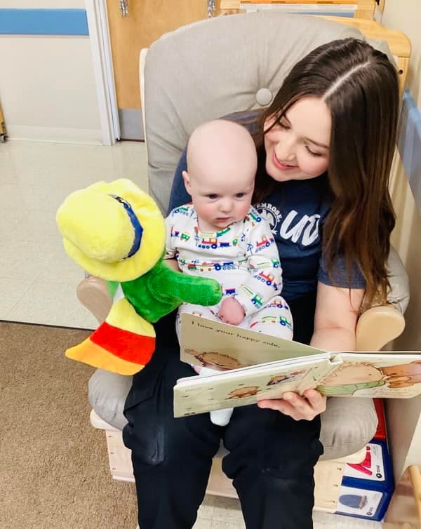 Infant child reading with her teacher in infant classroom at Eagle Ranch preschool.