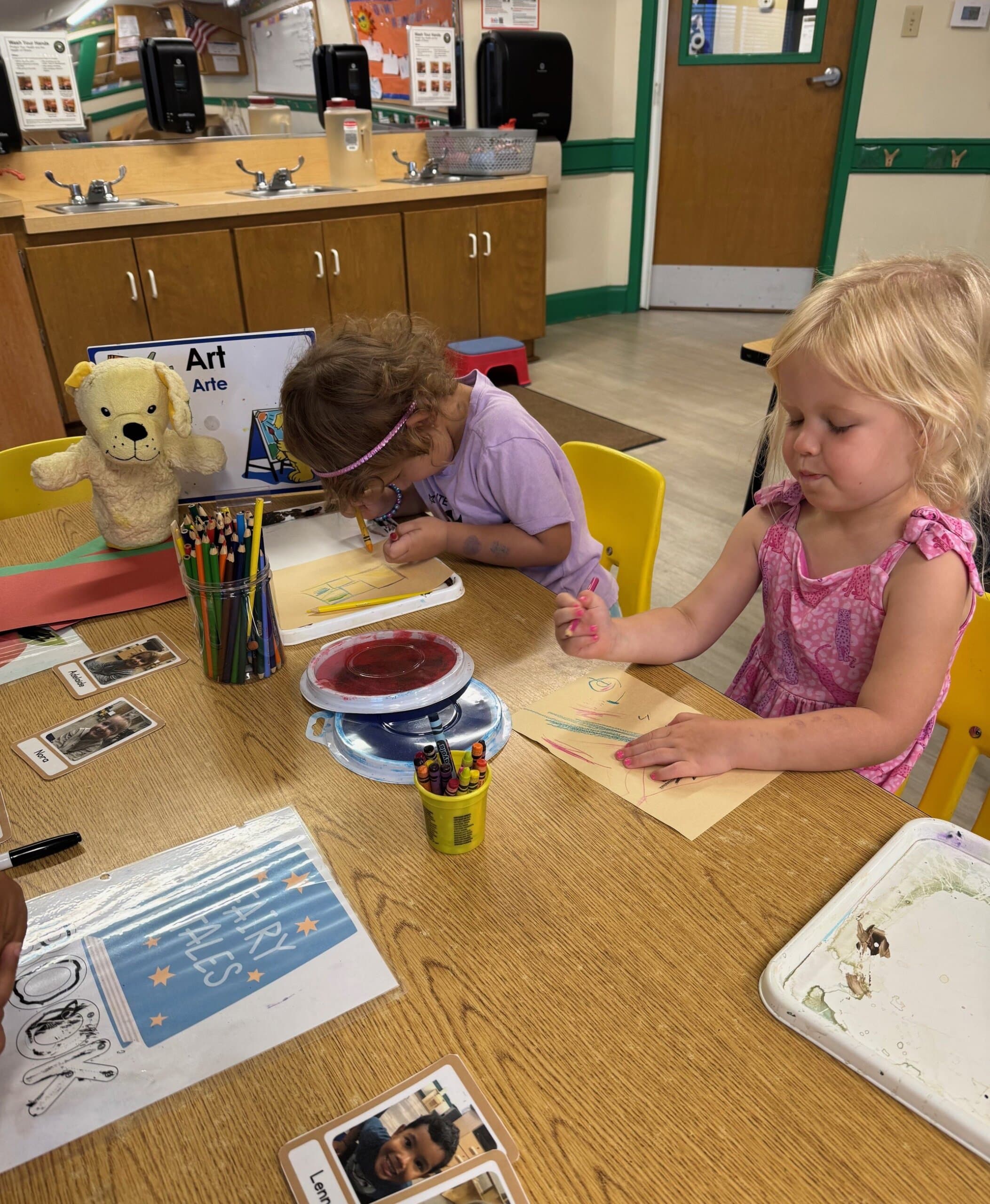 Preschool children creating art using a variety of supplies and mediums, including paint, markers, and collage materials, fostering creativity and fine motor development