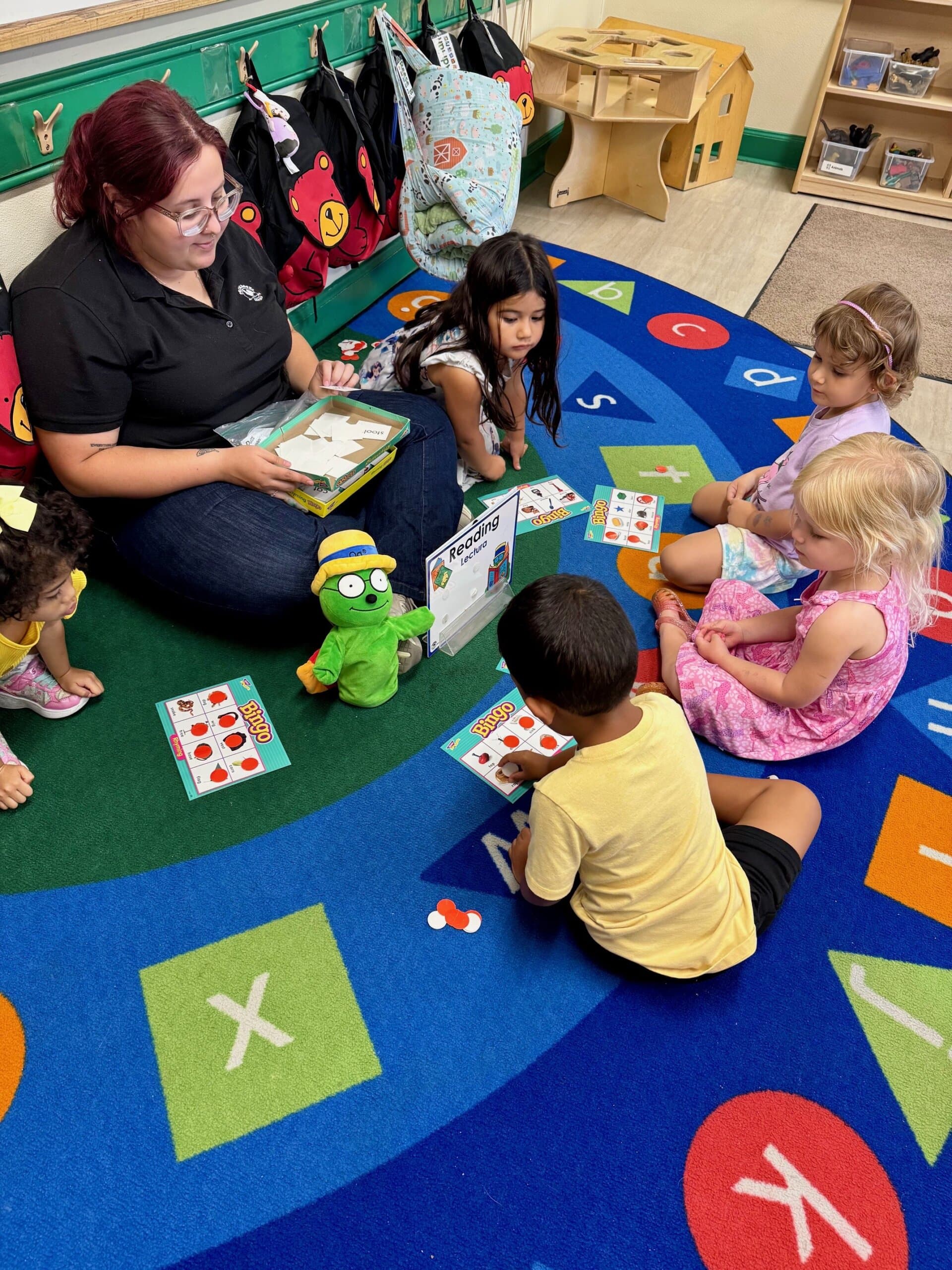 Preschool aged students playing bingo with their teachers, using letter and word cards to build early literacy skills through interactive and fun group learning