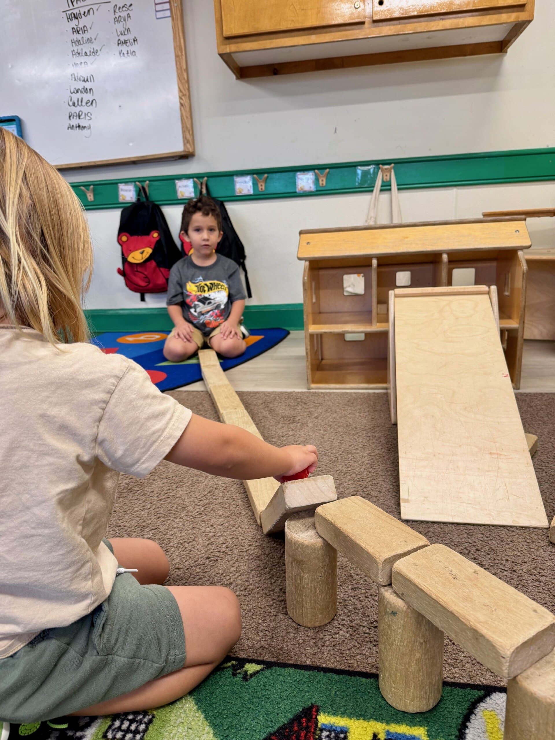 Children playing in the block center, building ramps with blocks to explore movement and gravity