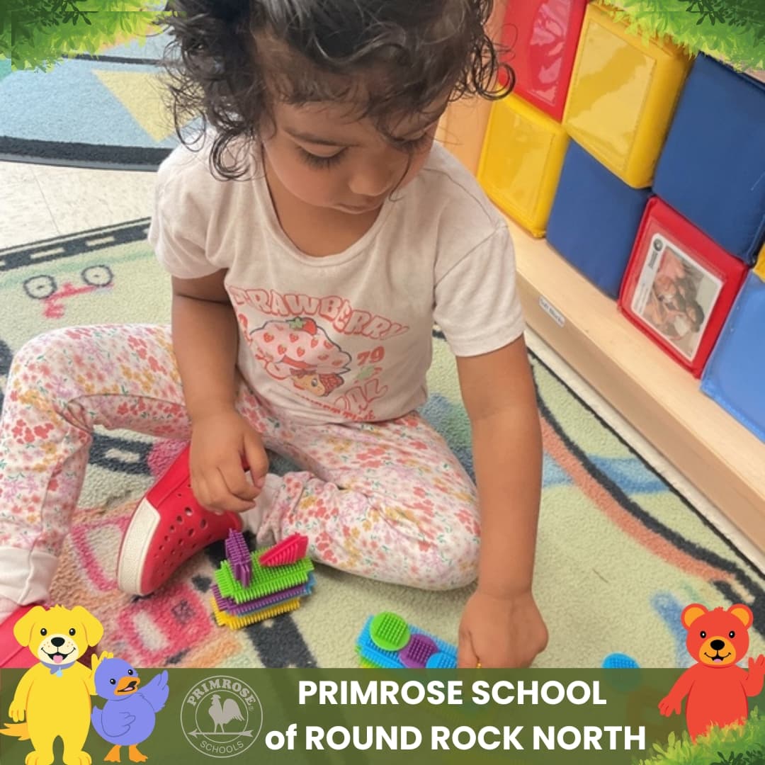 Child at Primrose School of Round Rock North building colorful sensory blocks during a hands-on classroom activity.