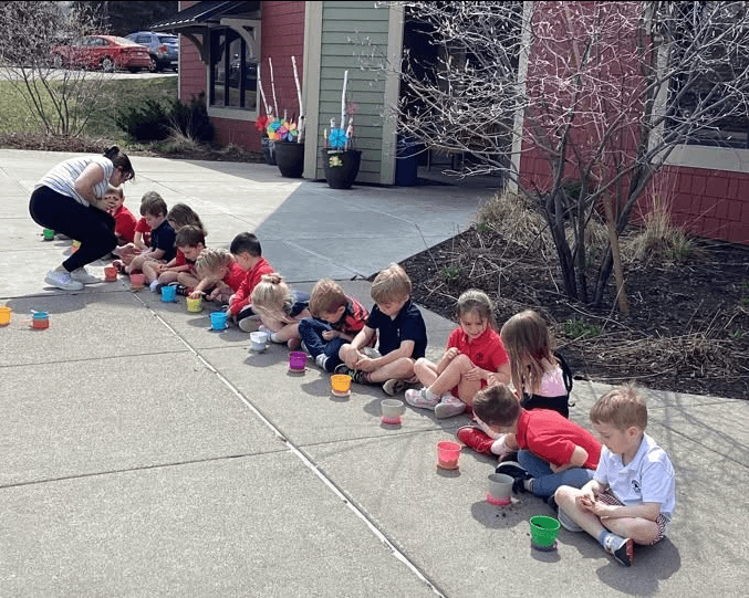 children sitting in front of school planting plants 