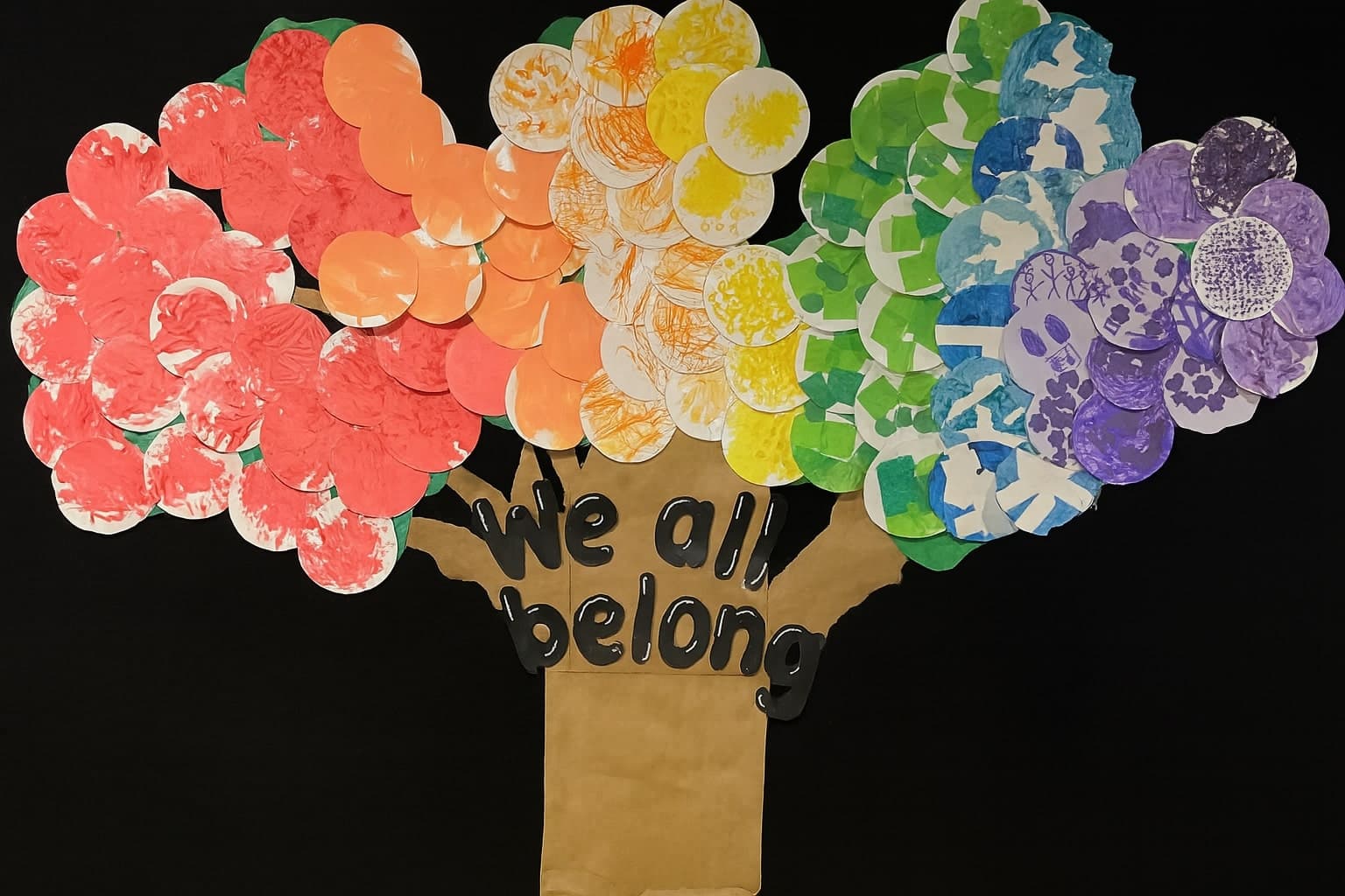 Handmade classroom mural of a tree with colorful paper circles and "We All Belong" message, created by children at Primrose School of Eagan preschool in Eagan, MN