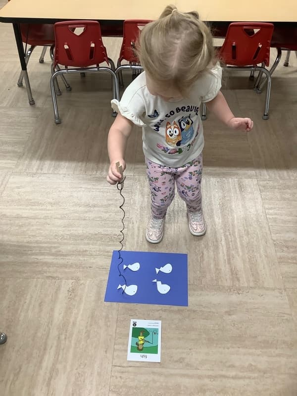 Young child playing a magnetic fishing game during hands-on classroom learning