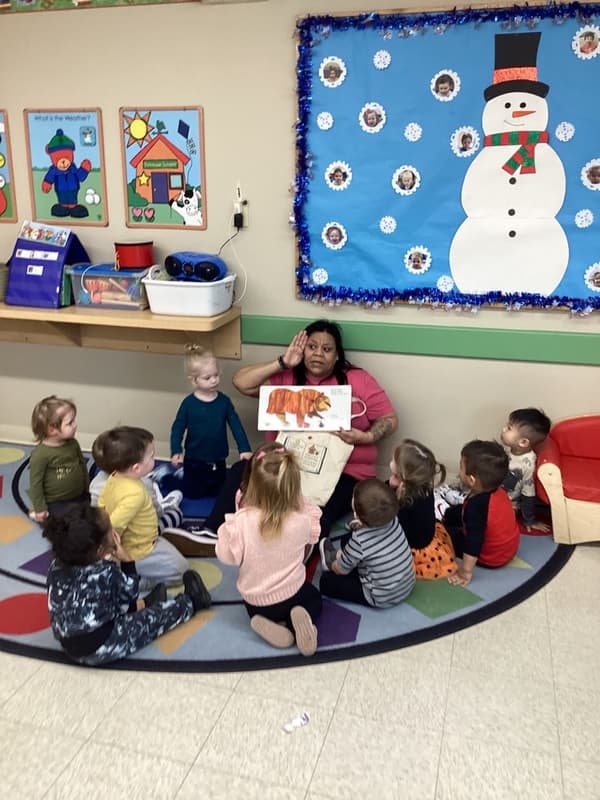 Two year olds participating in circle time routines with their teacher at Fort Worth childcare center.