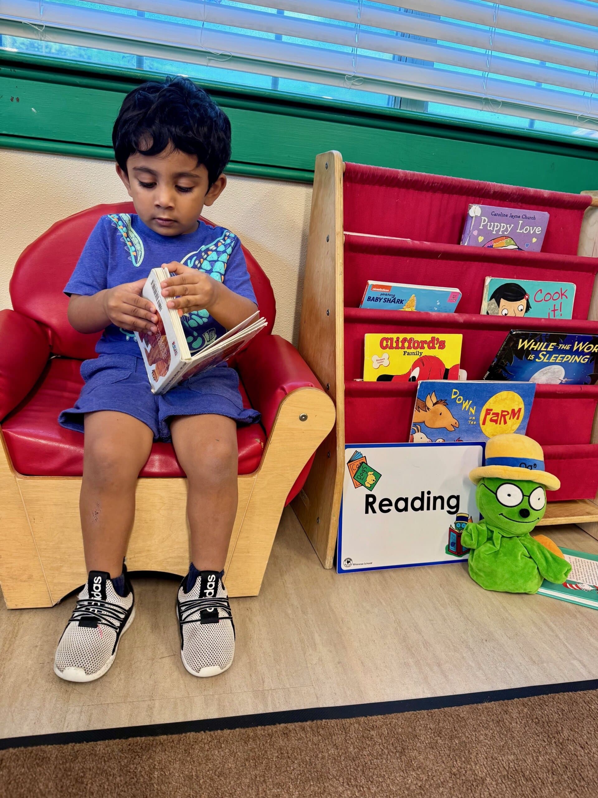 Child reading in the classroom reading center while using a puppet designed to support early literacy skills and storytelling engagement
