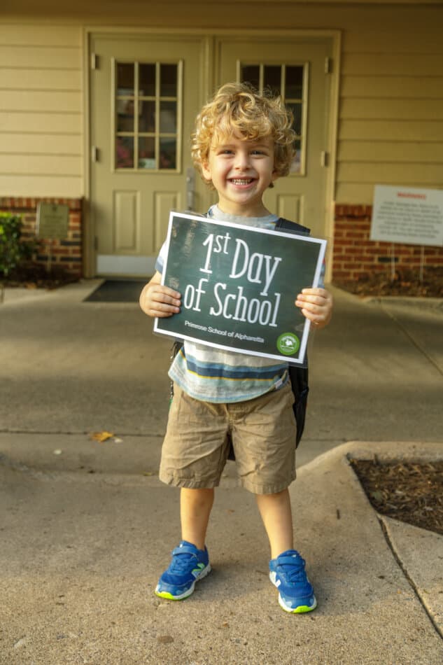 child holding a sign that says first day of school