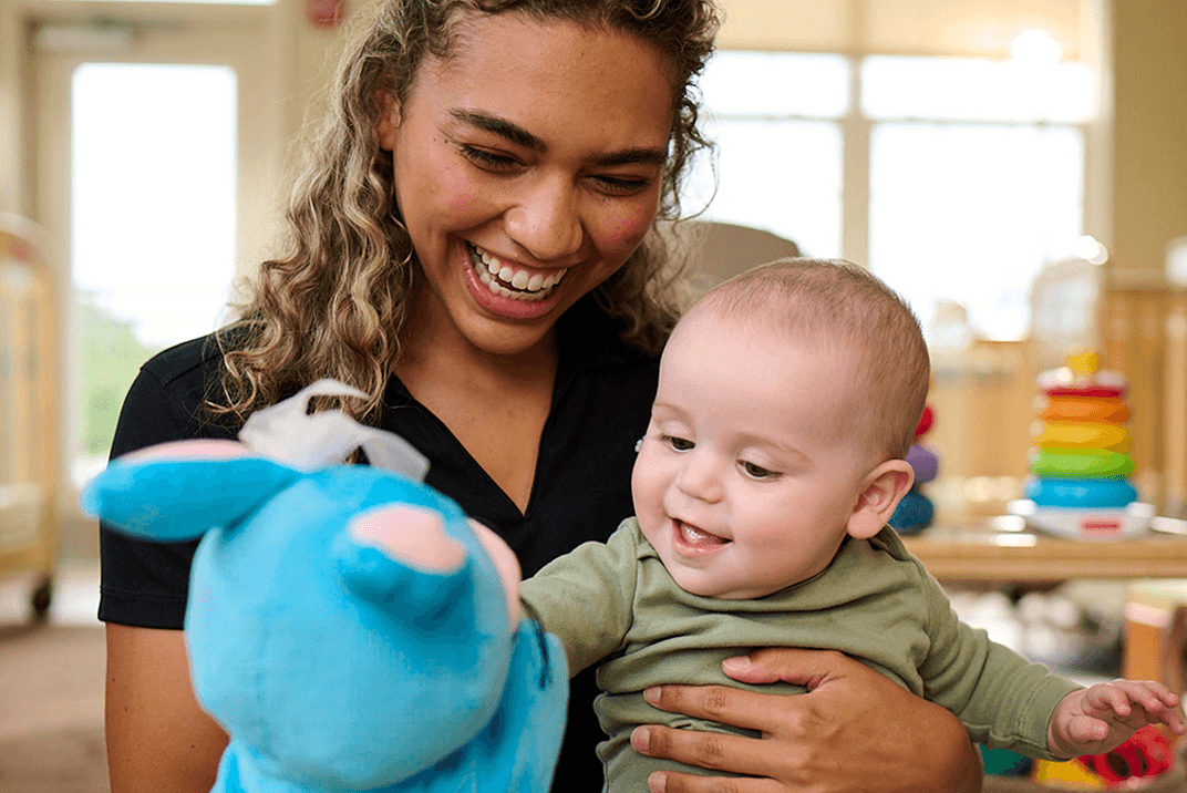 Primrose teacher playing with infant in the daycare room