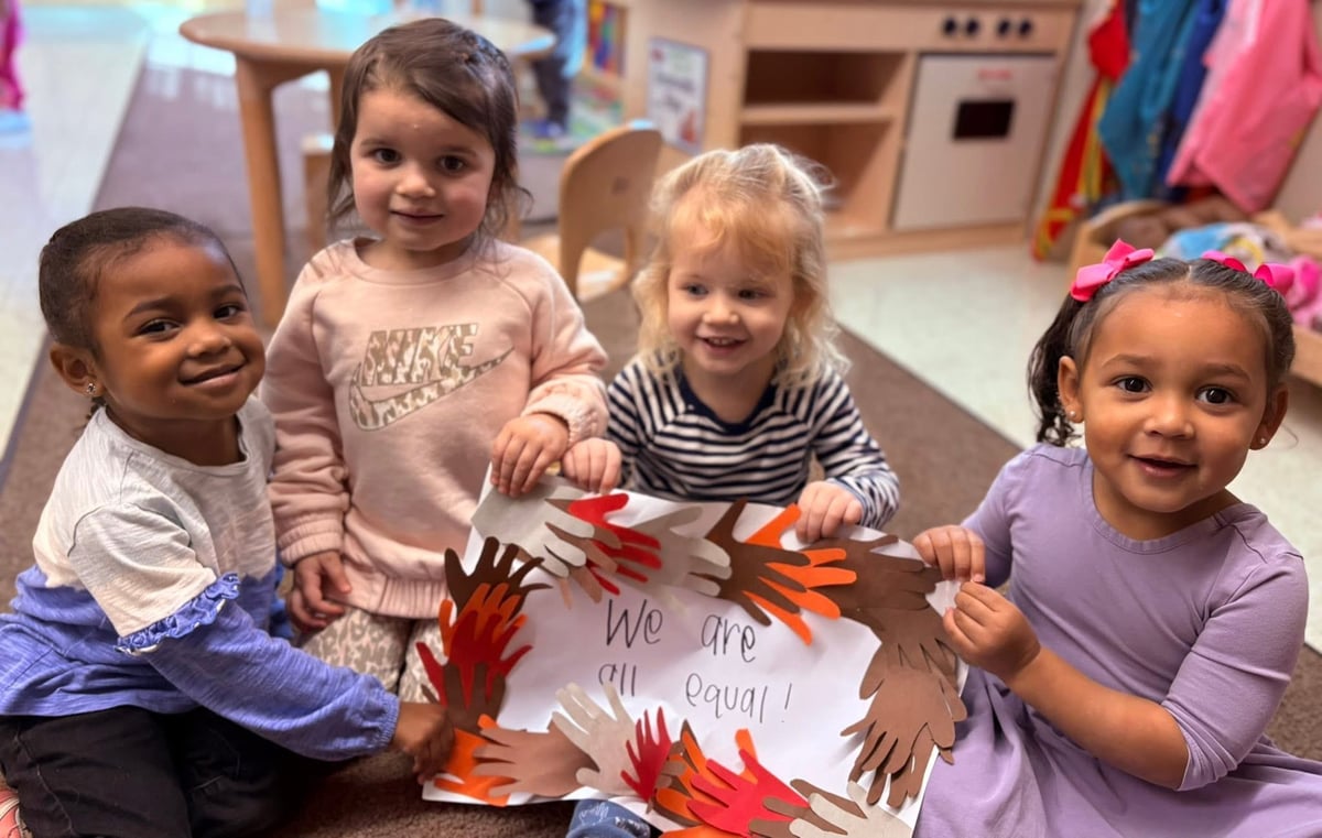 four children holding a paper craft that says we are all equal
