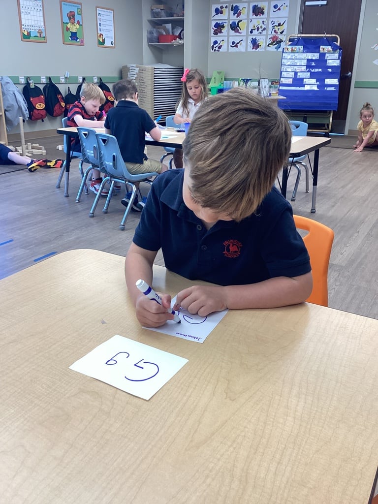 child in blue shirt looking at letter G