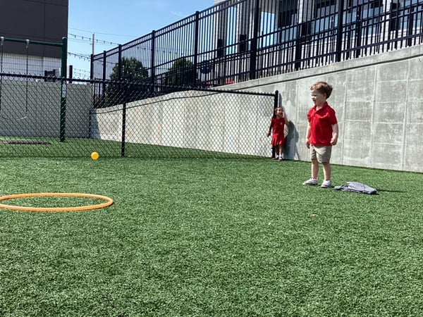 child in red shirt standing outside