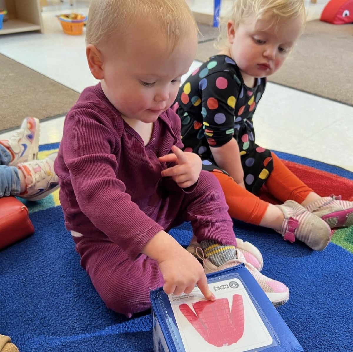 Infant student pointing to jacket in book