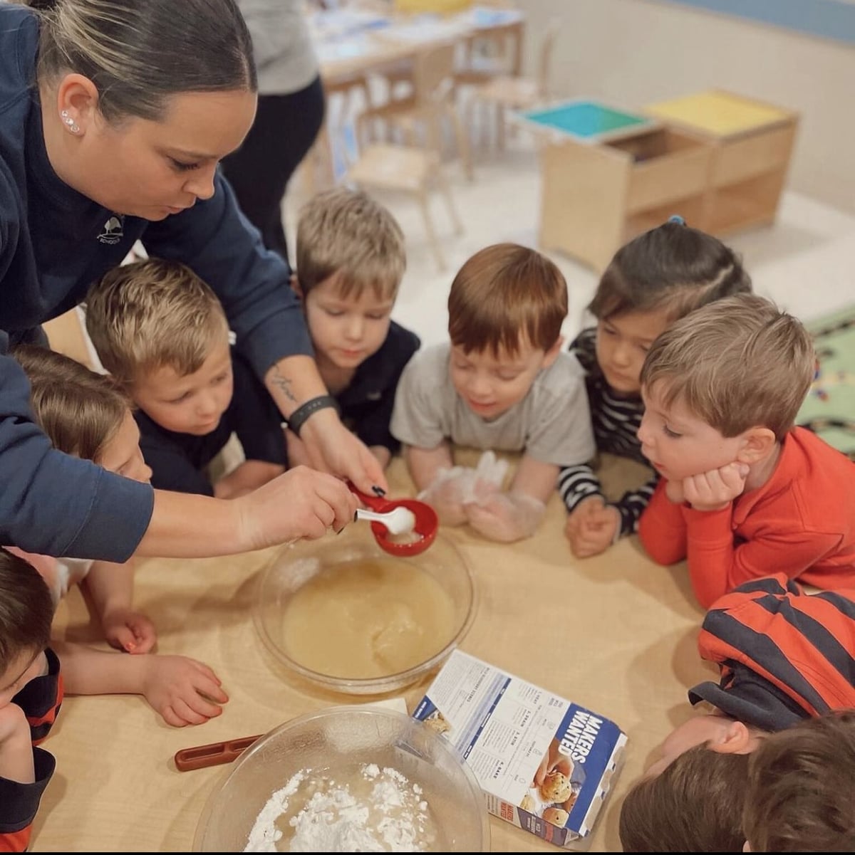 Students watching teacher pour baking ingredients into measuring cup