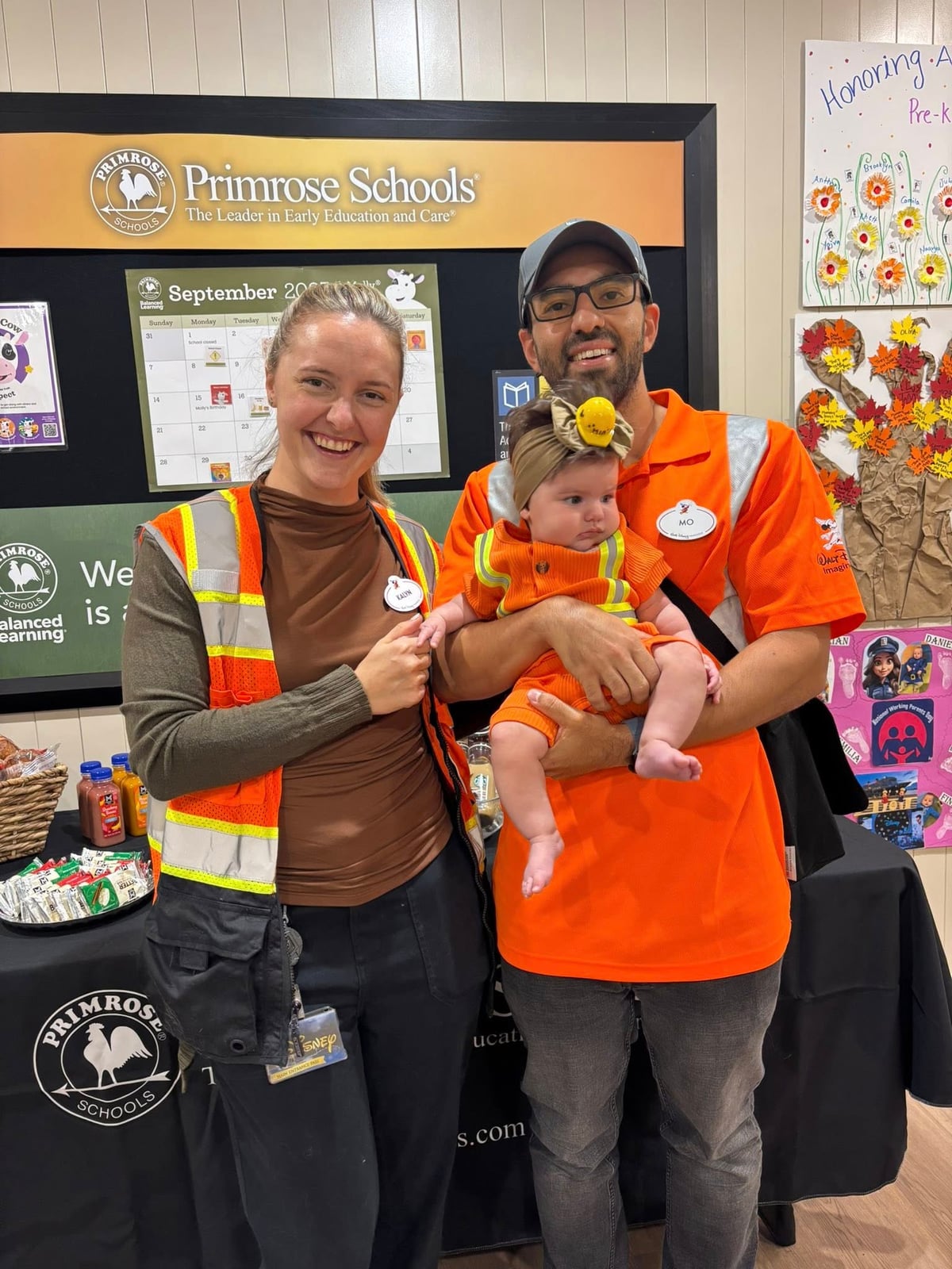 two adults and a baby in orange 