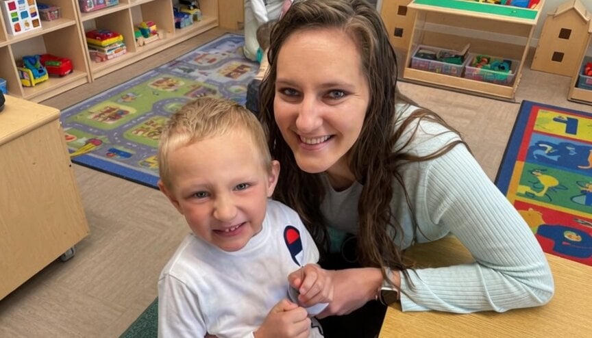 A Primrose School of Eagan staff member smiles with her child in the classroom — one of many families who love Primrose School of Eagan enough to make it part of their everyday life.