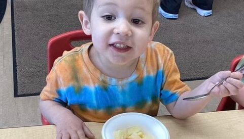 Early preschool student eating a fruit salad 