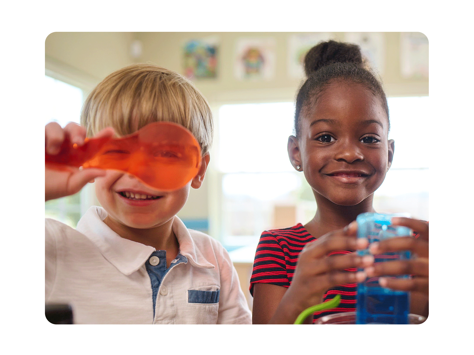 Primrose students looking into magnifying glass and smiling at camera