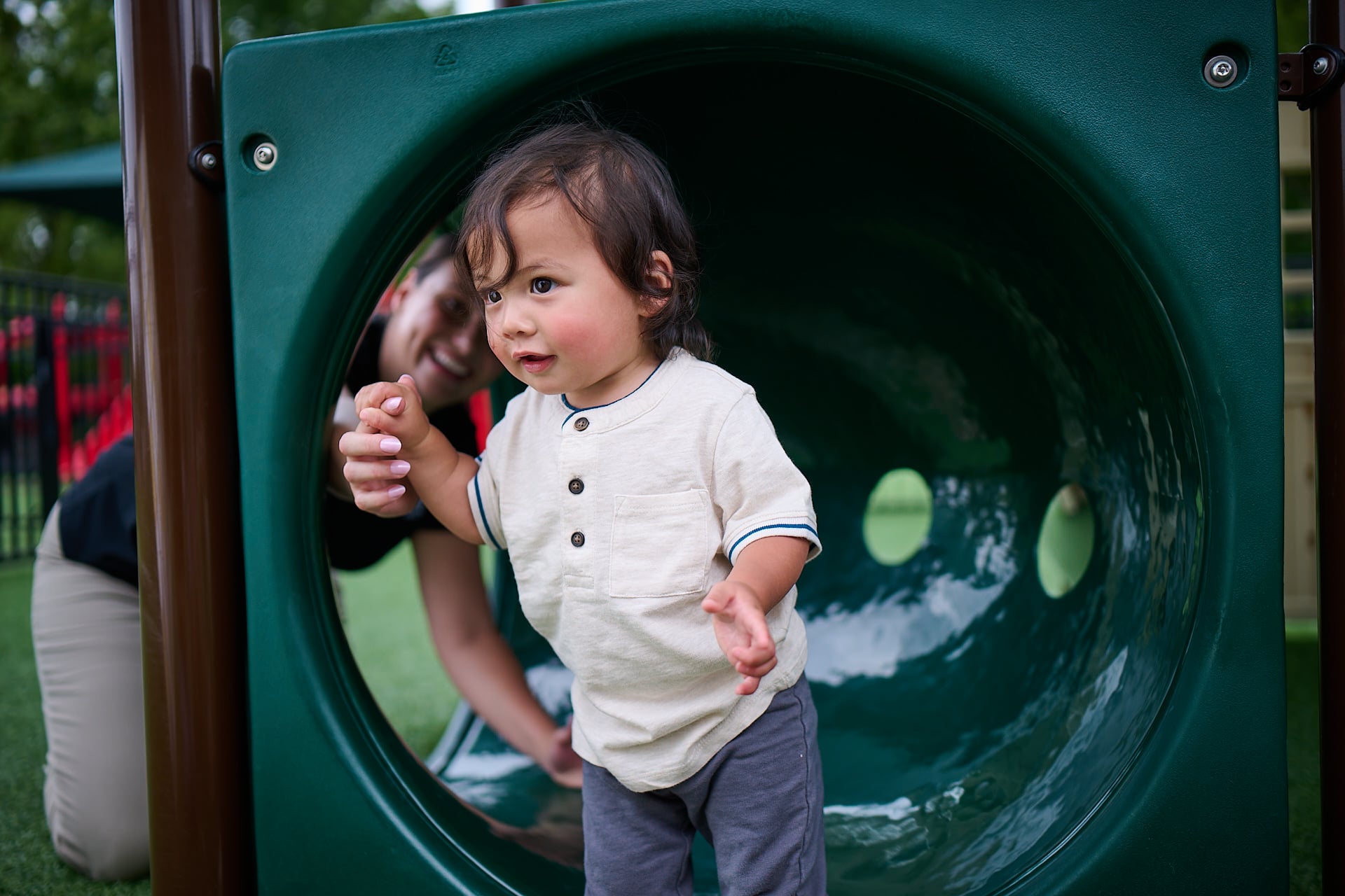 toddler playing on playground with teacher