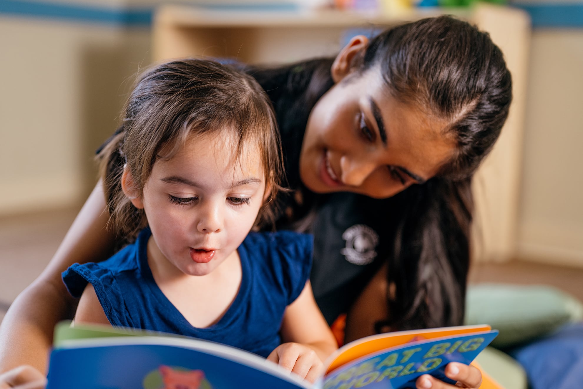 teacher reading a book to a toddler child