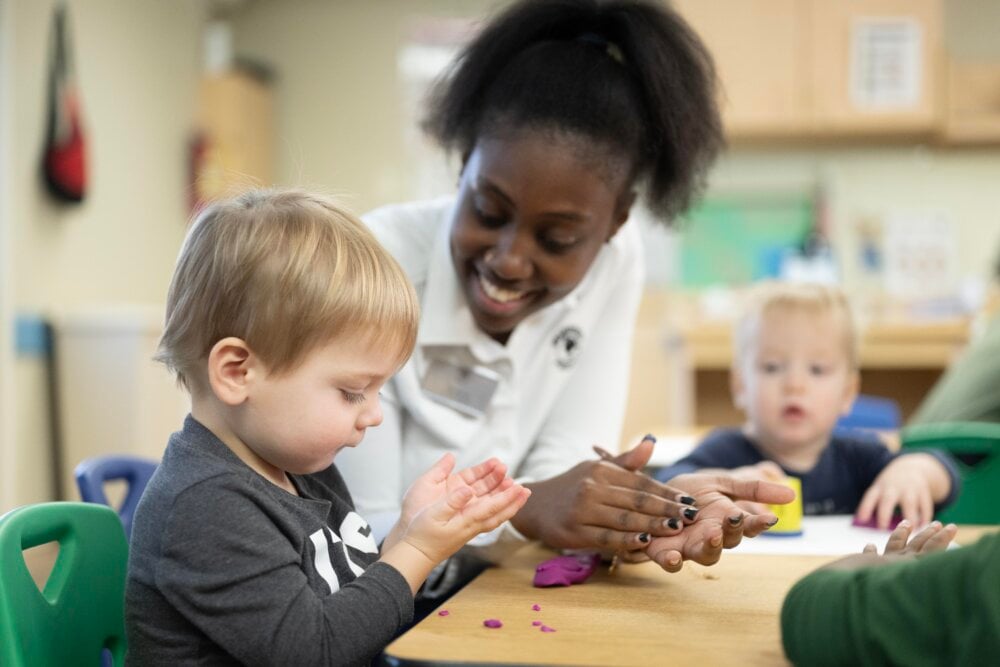 teacher helping toddler child