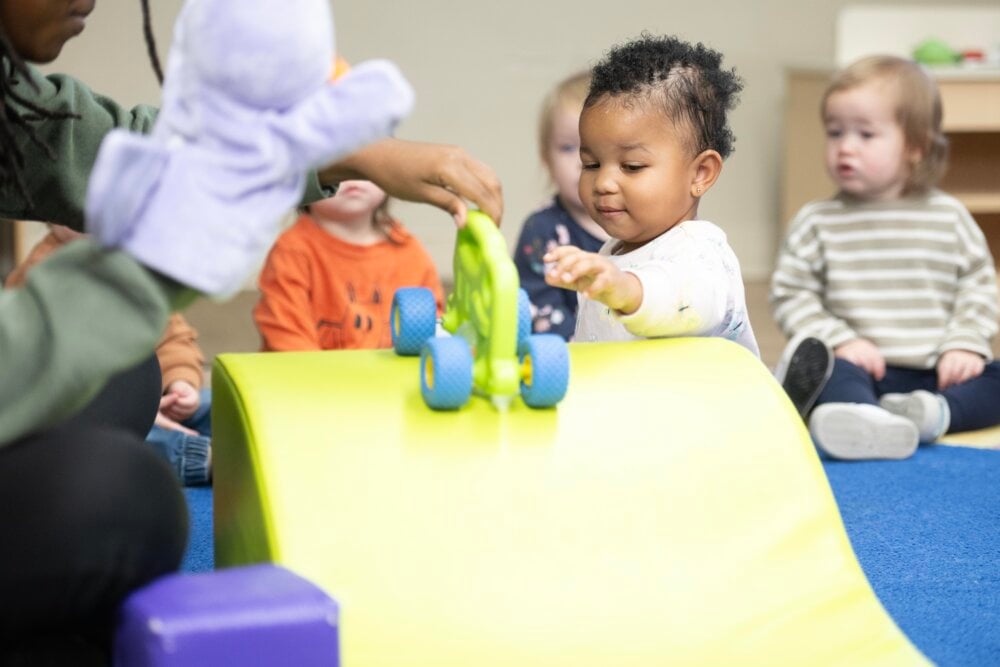 toddler child rolling toy down a ramp