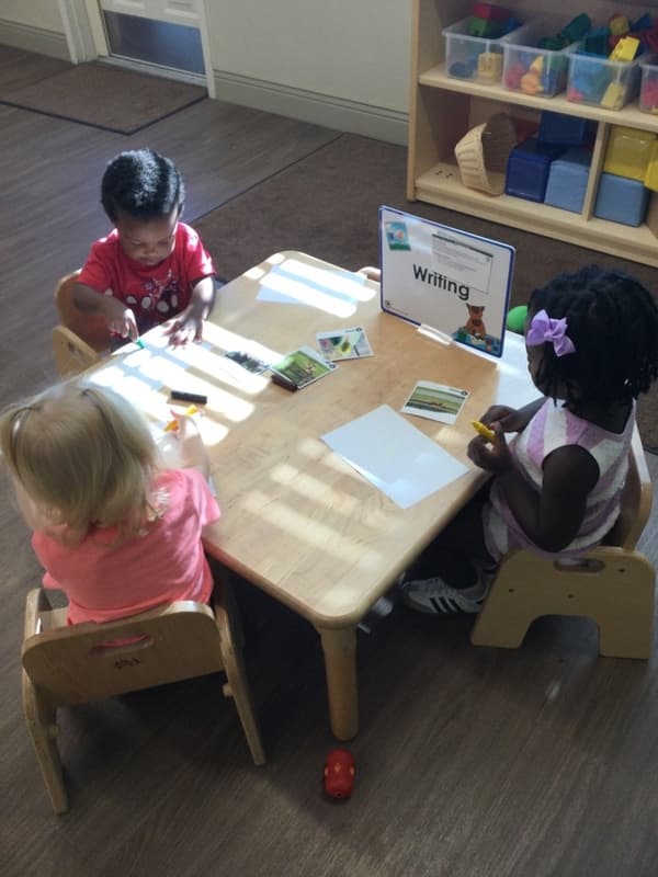 Two year olds at Primrose Fort Worth practicing early writing skills at a classroom literacy center.
