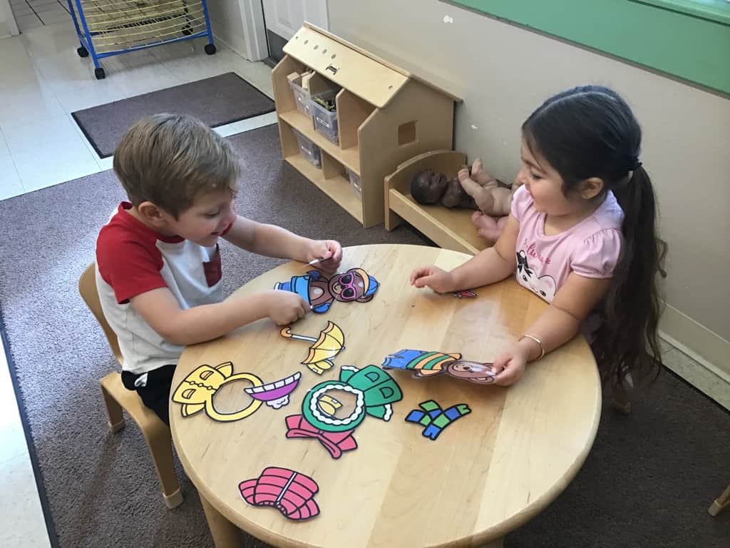 two children playing together in a class and smiling
