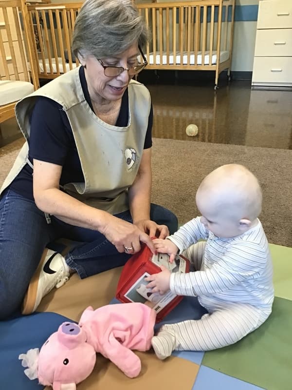 teacher uses a photo cube to teach and infant