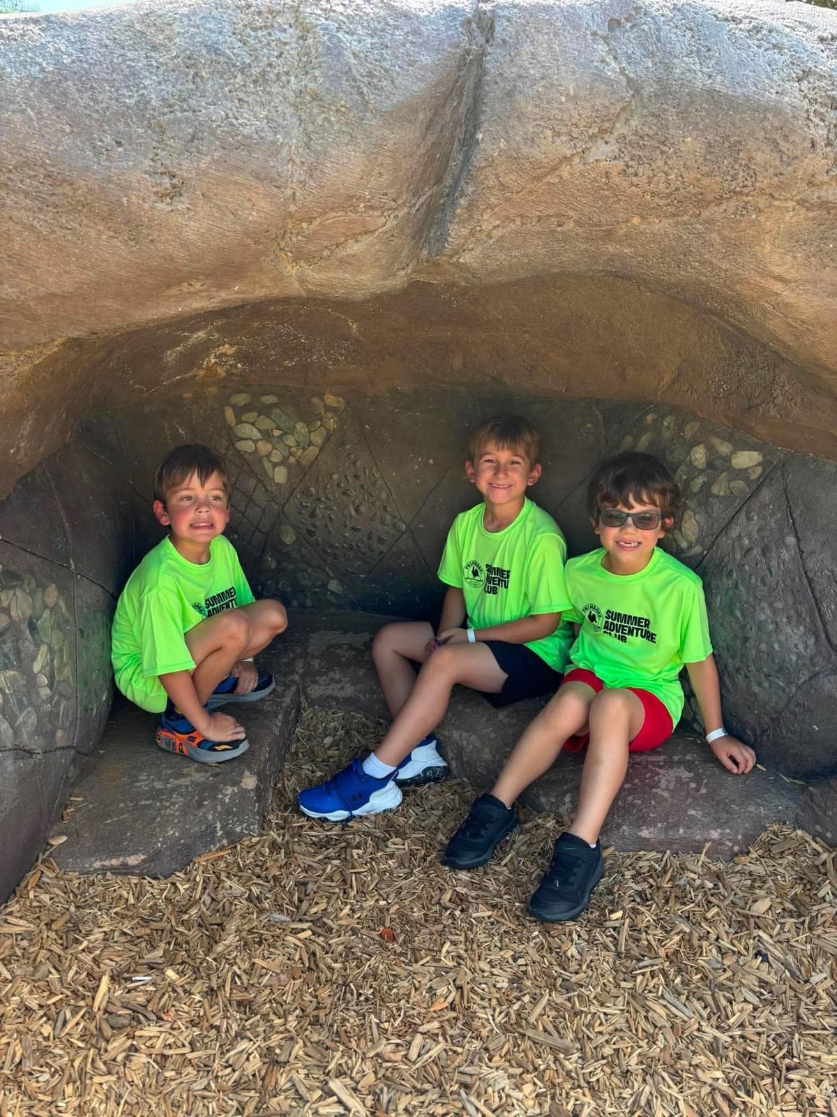 children sitting in a cave at the park