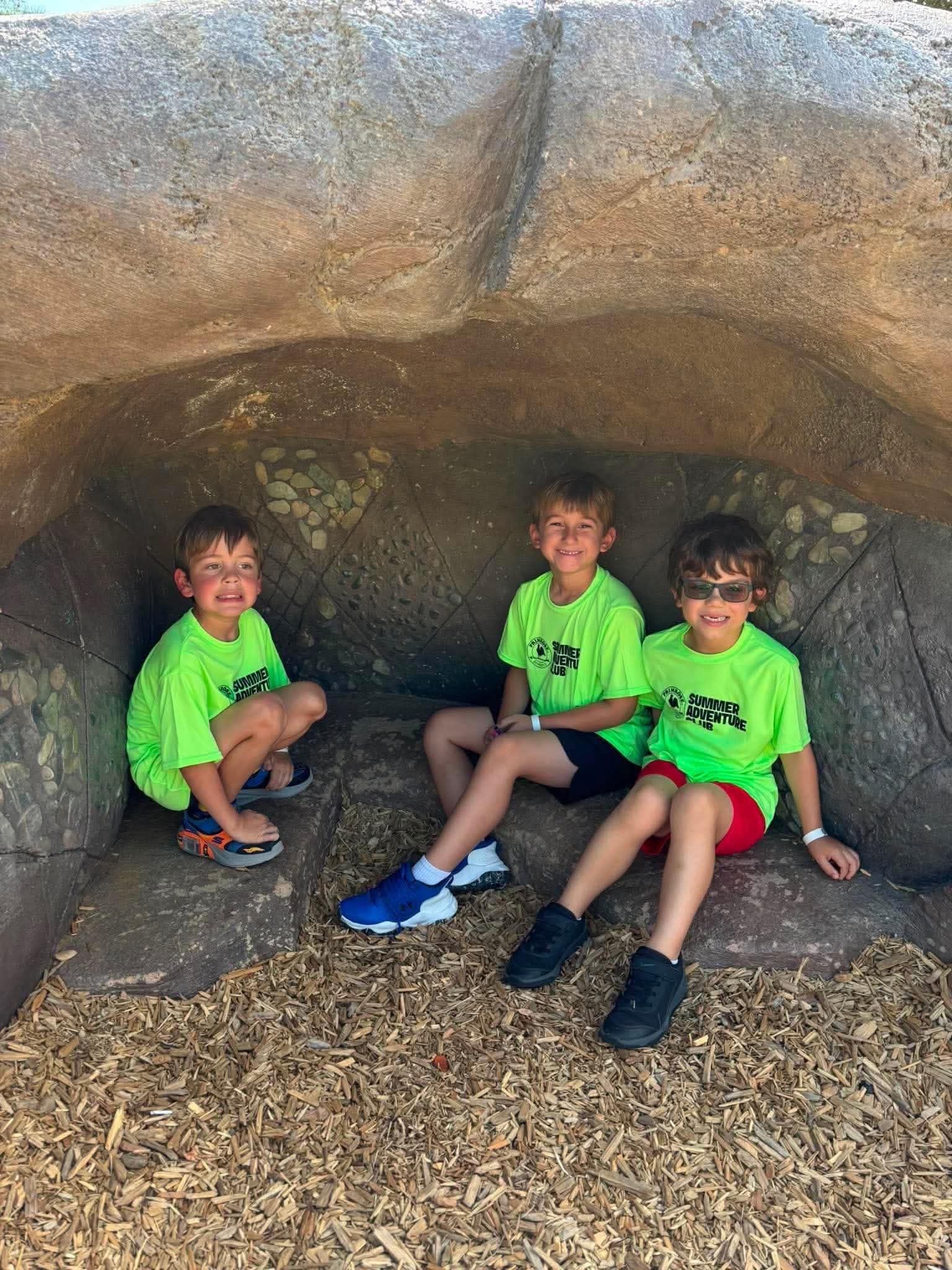 children sitting in a cave at the park