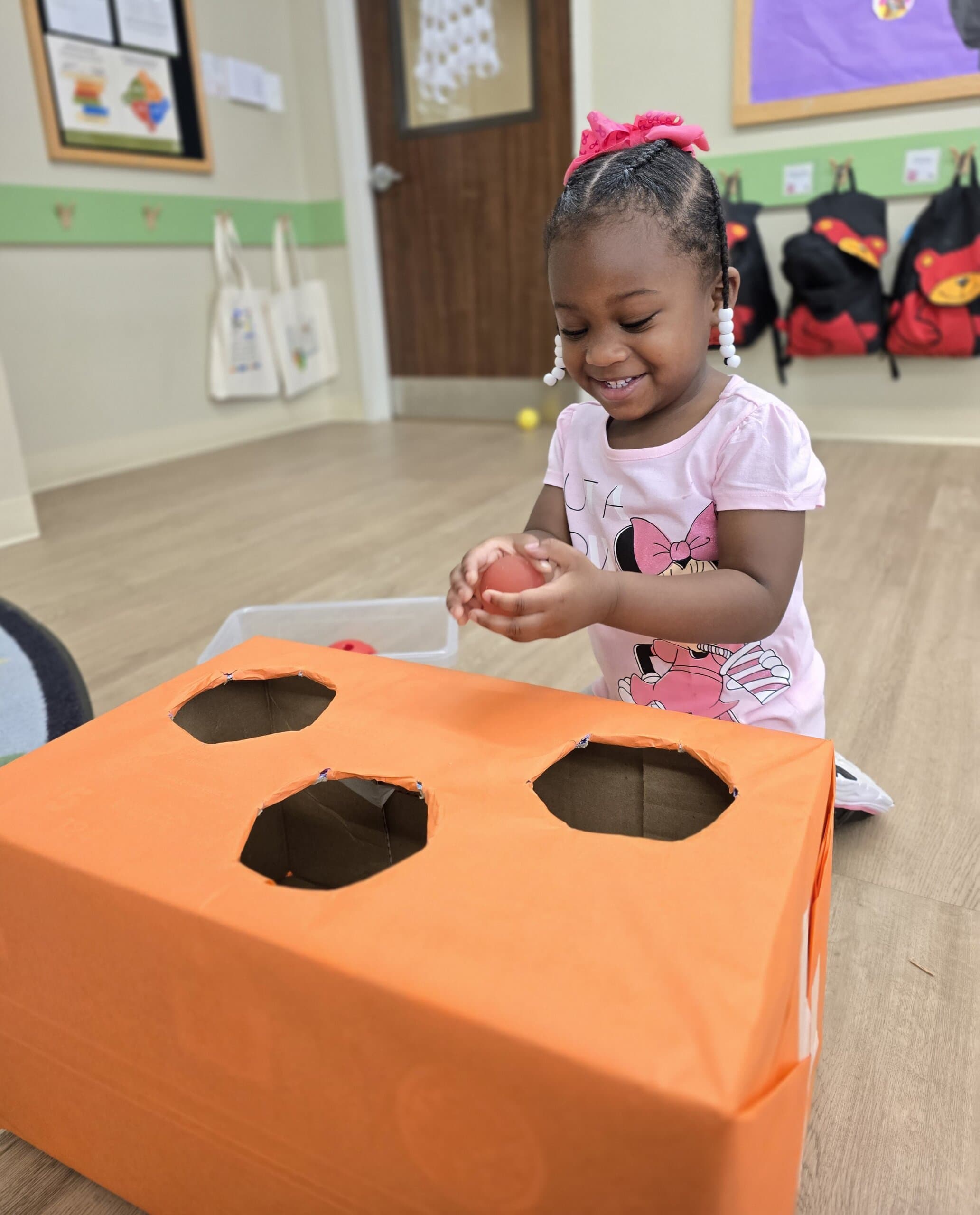 2 year old at Primrose School at Heritage exploring a fall-themed sensory box activity in the classroom in Keller, Texas.