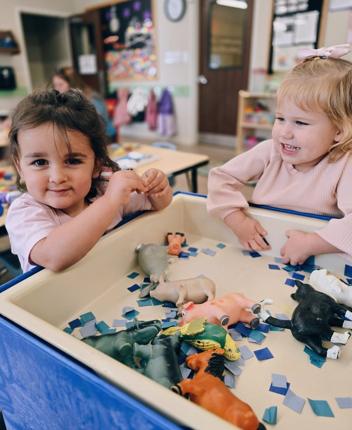 Two young girls exploring a sensory bin at Primrose School at Heritage in Keller, TX, engaging in hands-on learning and discovery.