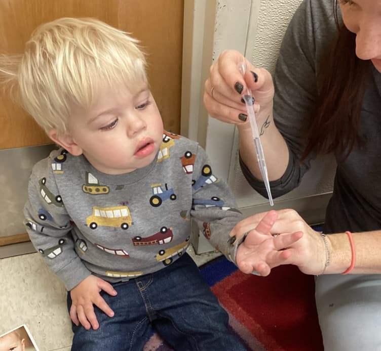 Toddler using an eyedropper with a teacher during a water exploration activity at Primrose School of Thornton