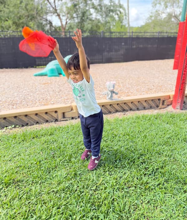 Child playing outdoors with a colorful scarf while practicing movement and coordination during outdoor exploration.