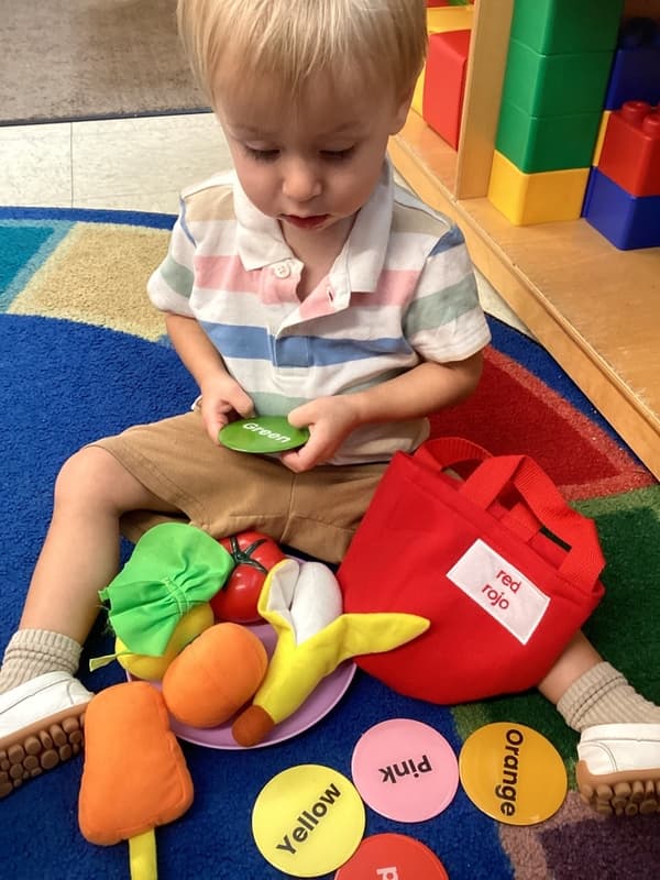 Young child learning color recognition through interactive play at Primrose School, building vocabulary, cognitive skills, and early learning foundations.