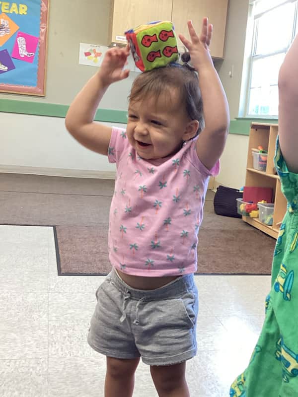 Toddlers practice balancing during our Thumbs Up! gross motor curriculum.
