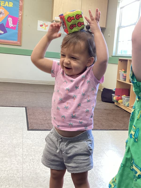 Toddlers practice balancing during our Thumbs Up! gross motor curriculum.