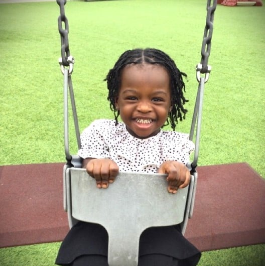 Happy Toddler swinging in a swing on the playground at the best and most trusted childcare center