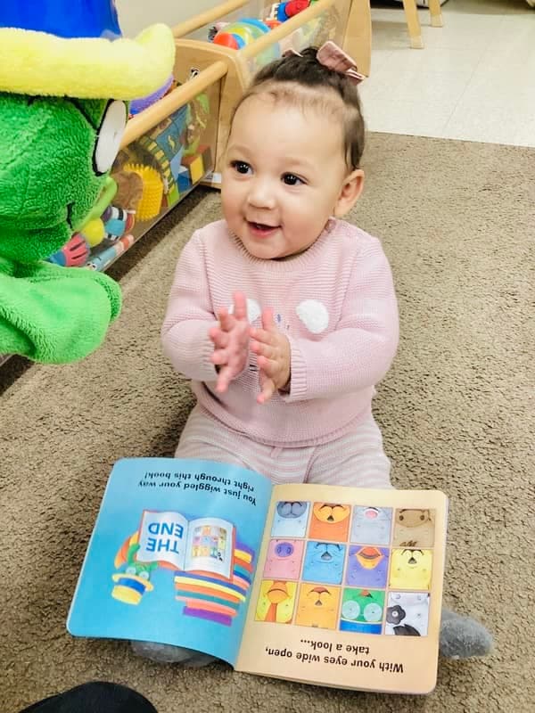 Infant child reading a book with Og the bookworm at Primrose schools, best early childcare in fort worth, saginaw, texas