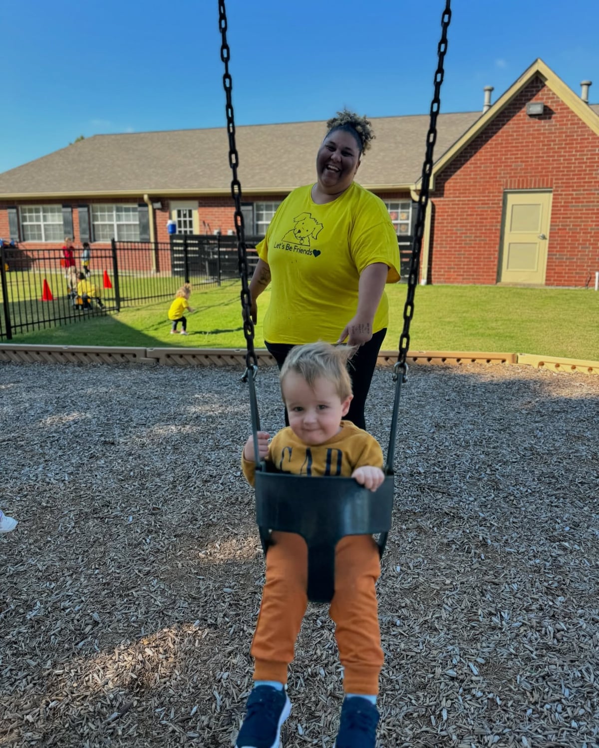 teacher swinging child on playground