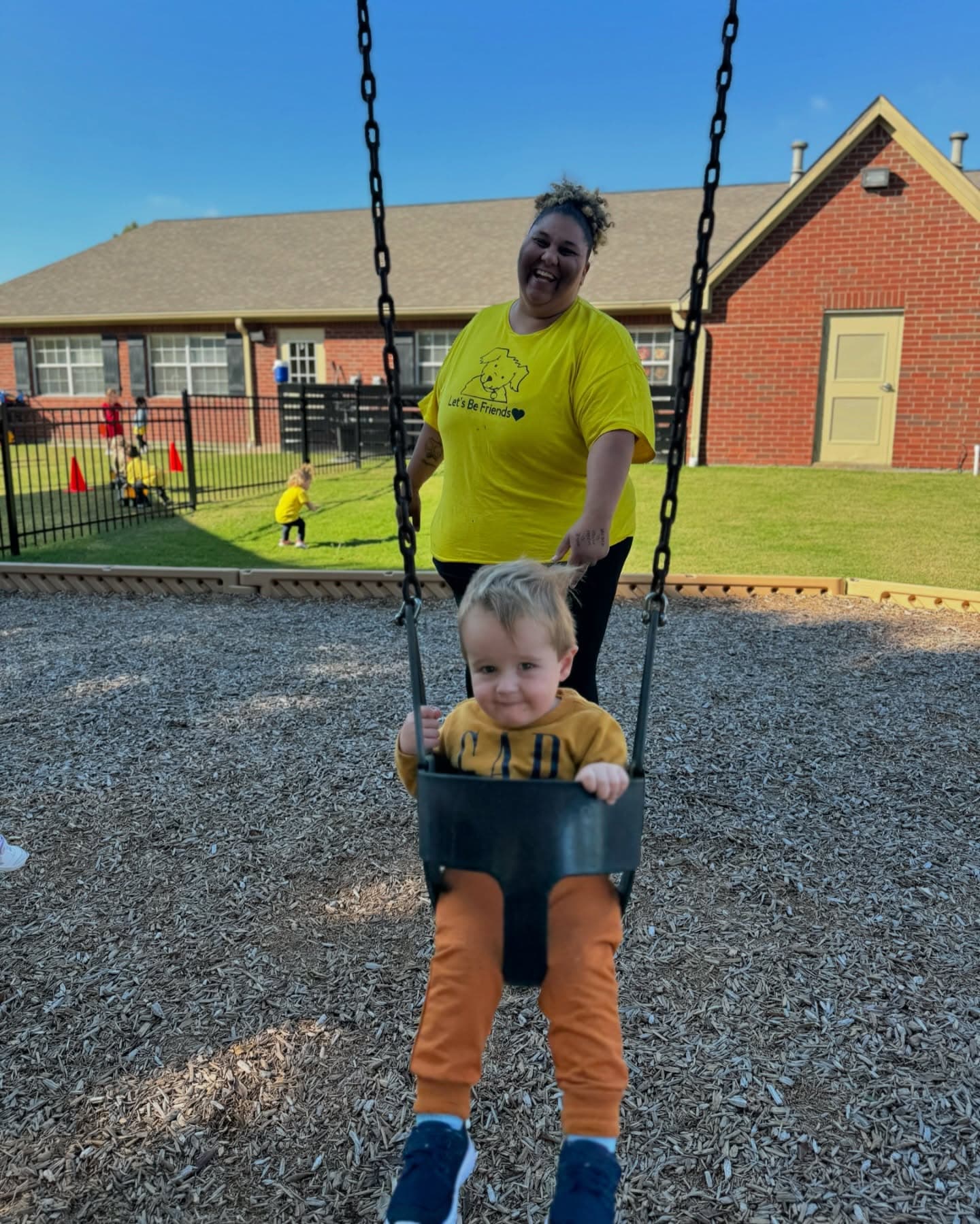 teacher swinging child on playground