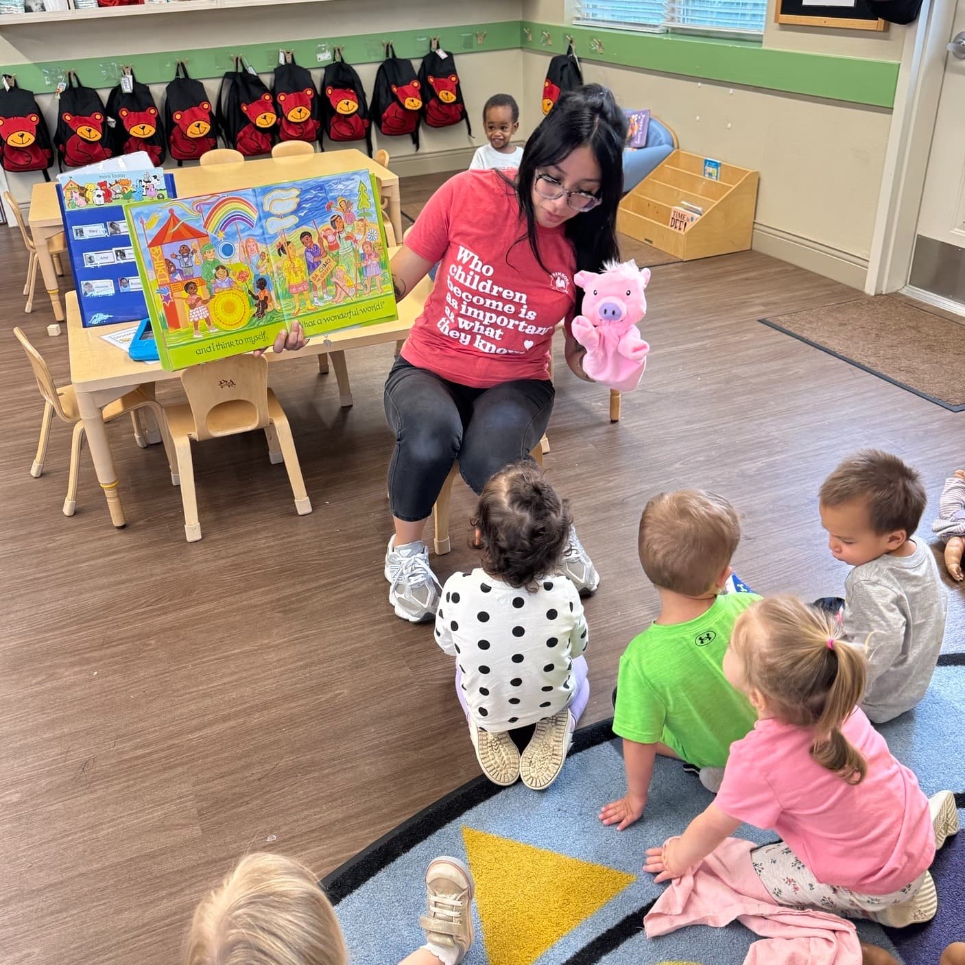 Loving teacher leading circle time with a storybook and puppet during early literacy activity.