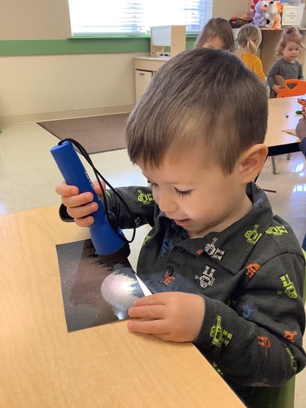 child using flashlight at daycare